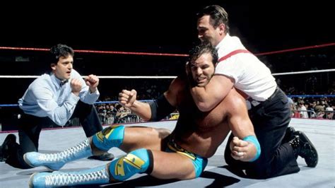 two men wrestling in an arena with one holding the other's leg up to his chest