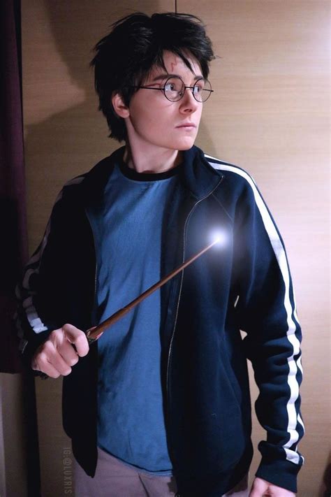 a man holding a wand in his right hand while wearing glasses and a blue shirt