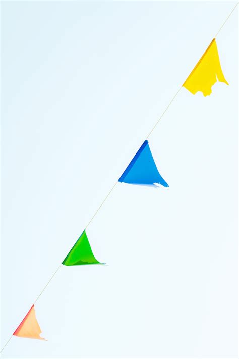 Multicolored string of pennant flags against blue sky · Free Stock Photo