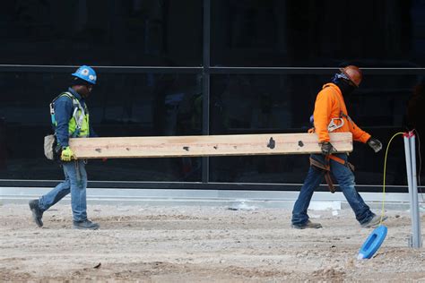 Workers carry a board at the Raiders Allegiant Stadium construction ...