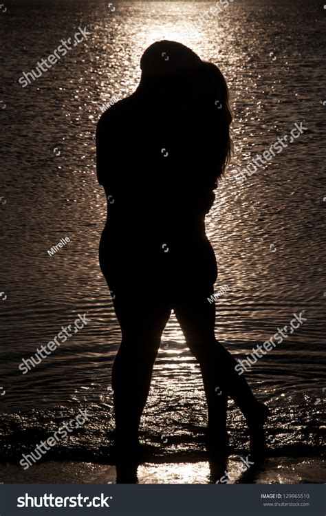 Young Couple Hug Silhouette On A Sea Beach Against Sunset Background ...