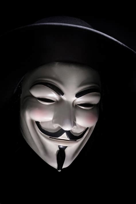 a smiling guy fawkes mask in shadow against a black background, guy ...