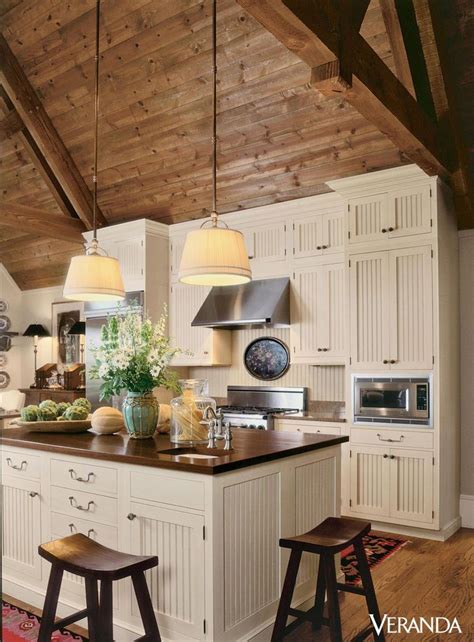 This rustic kitchen features a sloped wooden ceiling leading to ...