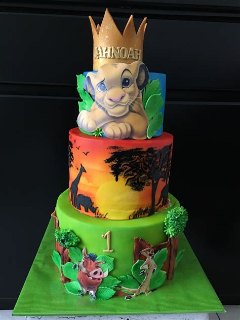 a three tiered cake decorated with animals and trees on it's sides, topped with a crown