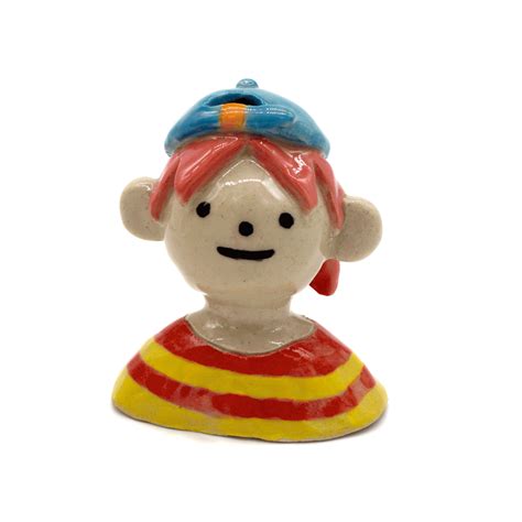 a ceramic figurine with a red and yellow striped shirt on it's head