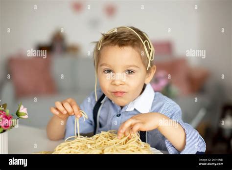 Cute preschool child, blond boy, eating spaghetti at home, making a ...