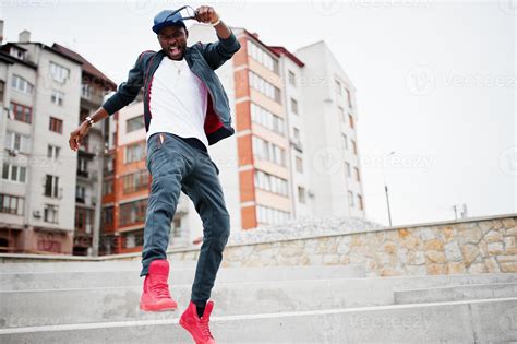 Portrait of jumping stylish african american man on sportswear, cap and glasses. Black men ...