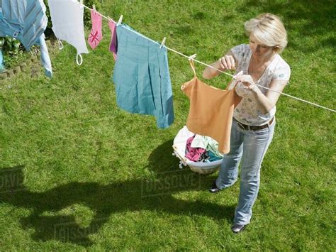 Woman hanging clothes on clothesline - Stock Photo - Dissolve