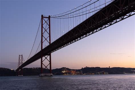 Premium Photo | Highlighted april bridge over the tagus river at sunset