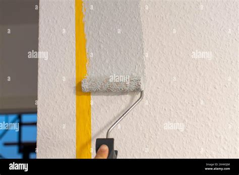 Painting the wall after taping it Stock Photo - Alamy