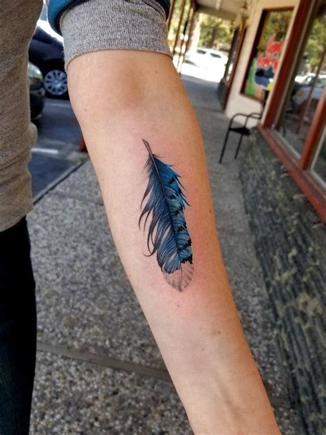 a person with a blue feather tattoo on their arm