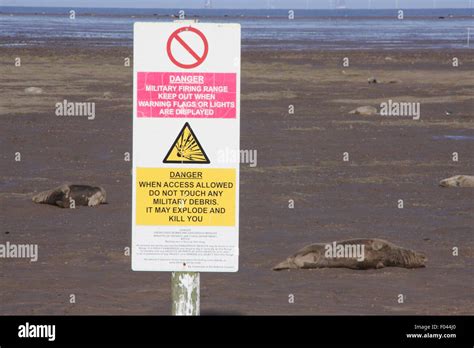 Signs on the mud flats at Donna nook nature reserve warning public to be aware of dangers of ...