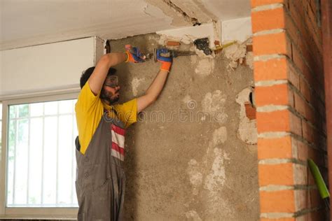 Young Builder Breaking Up a House Wall with a Hammer and a Chisel ...