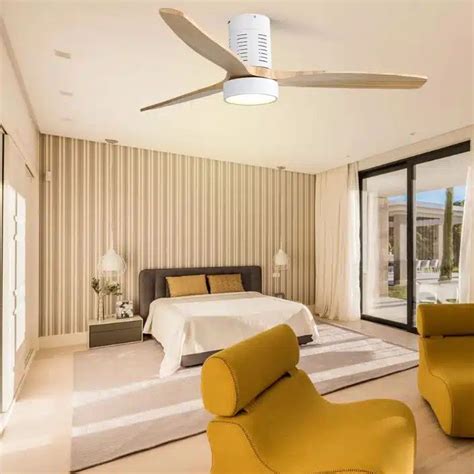 a bedroom with a ceiling fan and two chairs in front of the bed, next ...