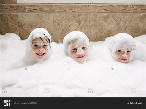 Three kids in a bubble bath stock photo - OFFSET