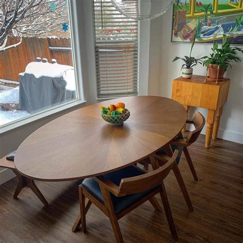 a bowl of fruit sits on top of a wooden table in front of a window