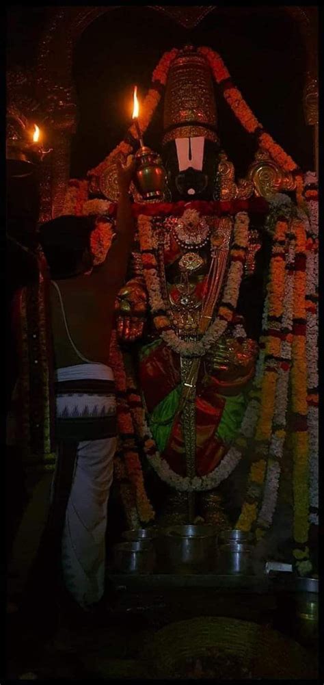 a man standing in front of a statue with candles on it's face and head