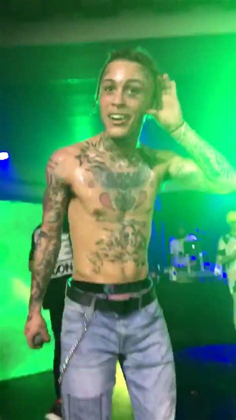 a man with tattoos on his chest standing in front of a microphone and green lights