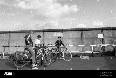 Children on bicycles pose in front of the border wall, 'Stop here ...