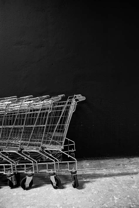 Empty shopping carts standing near black wall · Free Stock Photo