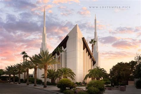 a large white building with palm trees in front of it and a sunset behind it