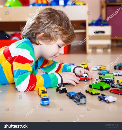 Little Blond Child Playing With Lots Of Toy Cars Indoor. Kid Boy Wearing Colorful Shirt. Happy ...