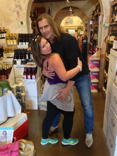 a man and woman hugging in a store with shelves full of wine bottles behind them