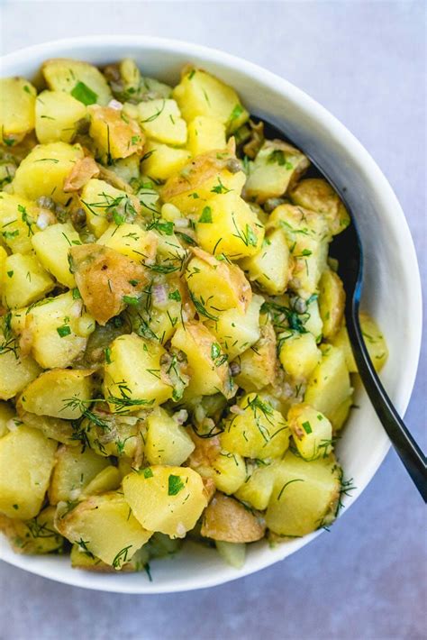 a white bowl filled with potatoes and herbs