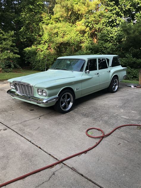 a mint green station wagon parked in a driveway with a hose attached to the front