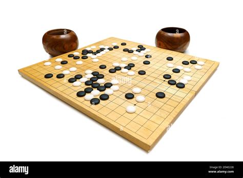 black and white stones on a ‘GO’ board made from wood on white ...