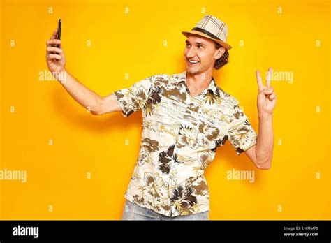 smiling male tourist traveler takes selfie on phone camera showing victory peace sign with his ...