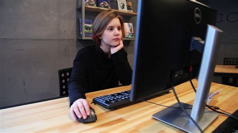 Young girl uses computer with interest while sitting at the table child education homework ...