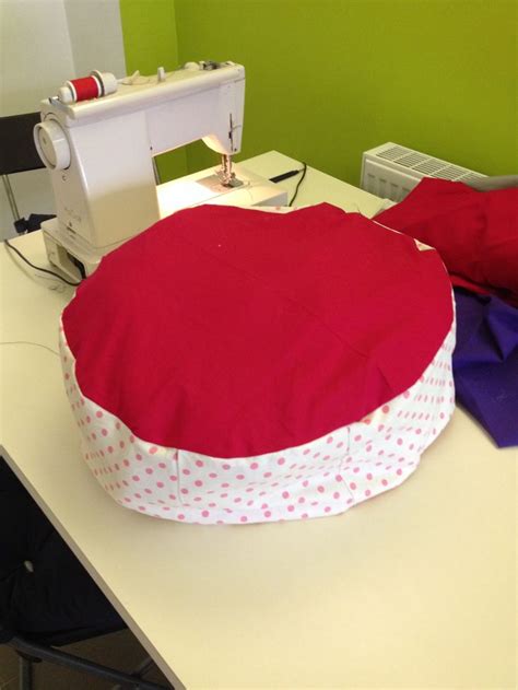 the sewing machine is sitting on the table next to the red and white round pillow