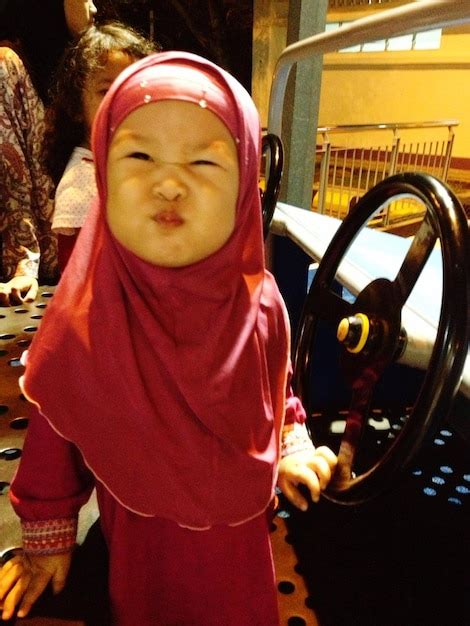 Premium Photo | Cute girl in hijab making face in car at amusement park