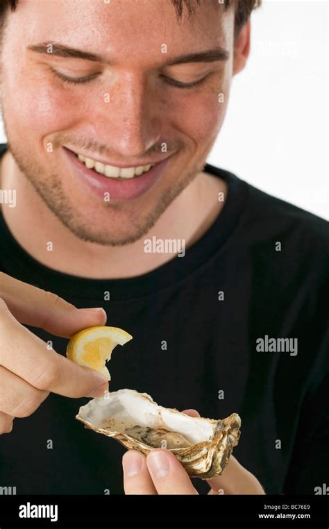 Man squeezing lemon juice on to a fresh oyster Stock Photo - Alamy