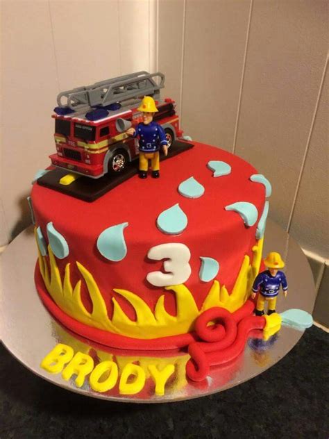 a birthday cake with firetruck and toy figures on top, sitting on a table