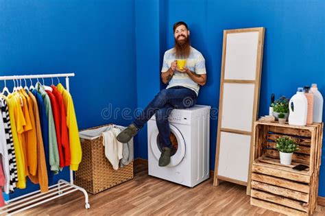 Young Redhead Man Drinking Coffee Waiting for Washing Machine at ...