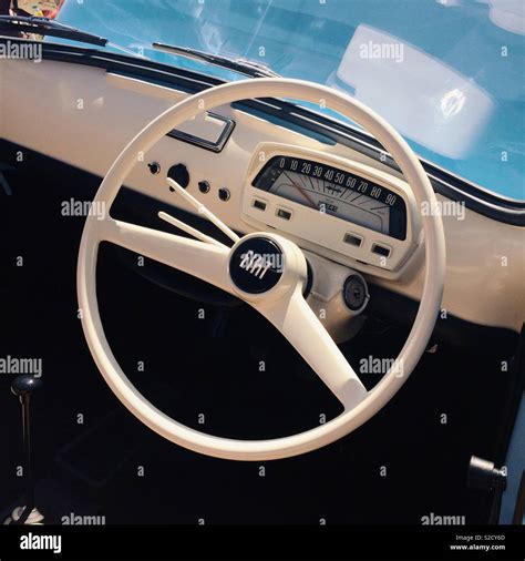 A white dashboard and steering wheel interior of a retro styled fiat ...