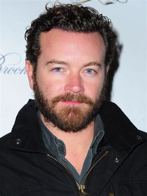 a close up of a person wearing a black jacket and beard with a blue eye