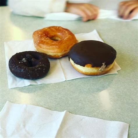 three doughnuts are sitting on napkins on the table, one is chocolate ...