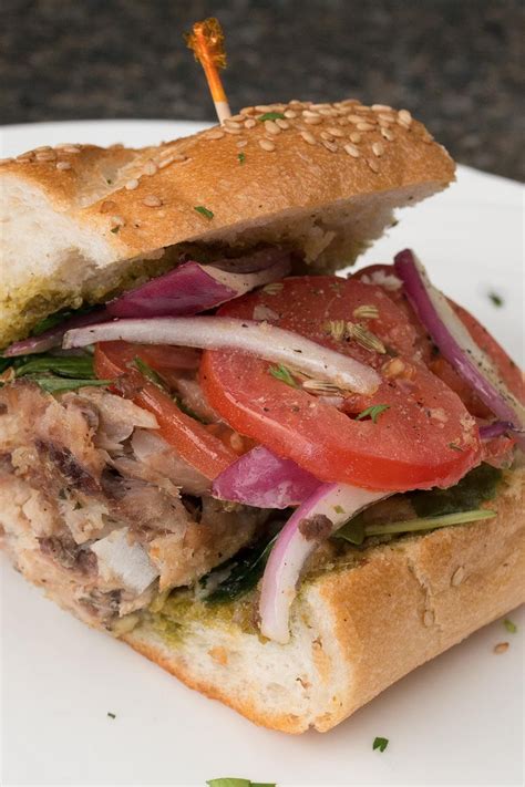 a close up of a sandwich on a plate with tomatoes, onions and lettuce