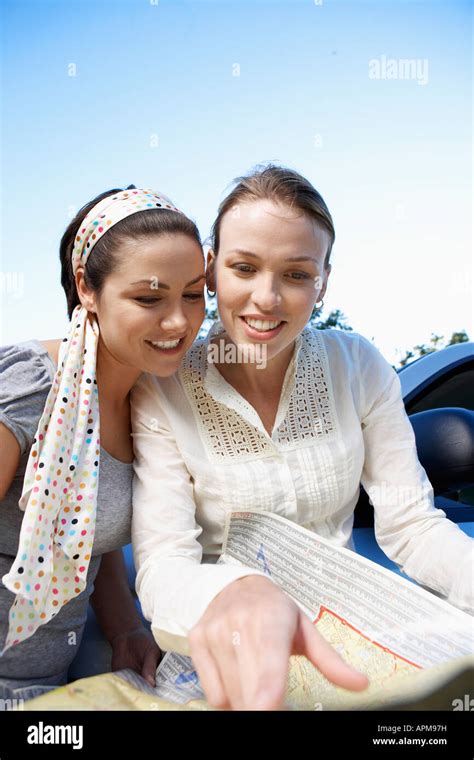 Two women reading road map Stock Photo - Alamy