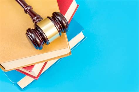 Premium Photo | Judge's wooden hummer on stack of law books on a blue background top view