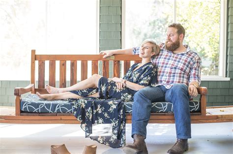 a man and woman sitting on a wooden bench in front of a window with ...