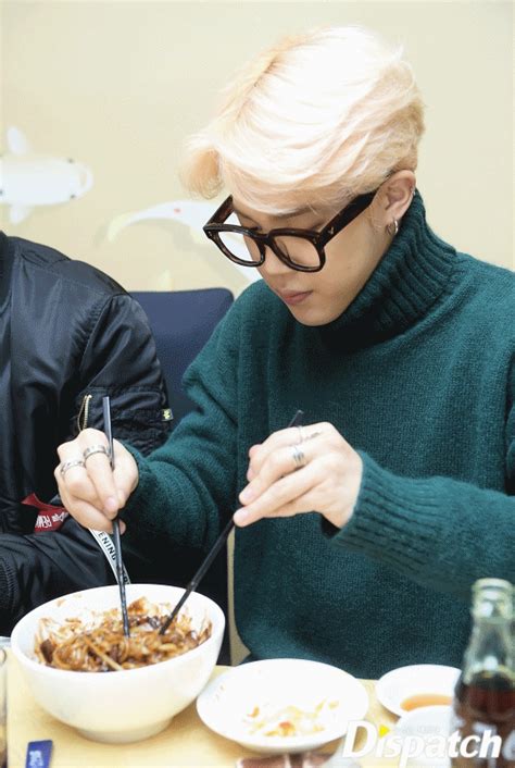 two people sitting at a table with food in front of them and one person eating from a bowl