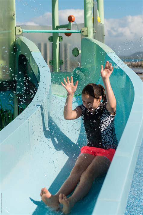 "Girl At A Waterpark Being Splashed With Water On A Slide" by Stocksy Contributor "Gillian Vann ...