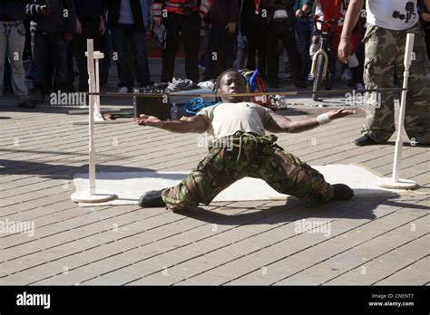 UK Young coloured man entertaining street crowd doing limbo dance under low bar Stock Photo - Alamy