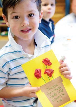 a young boy holding up a card with flowers on it