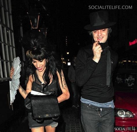 a man and woman walking down the street at night with an umbrella in their hand