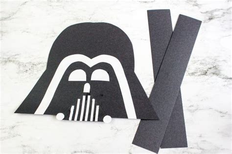 a darth vader paper cut out on top of a marble table with scissors